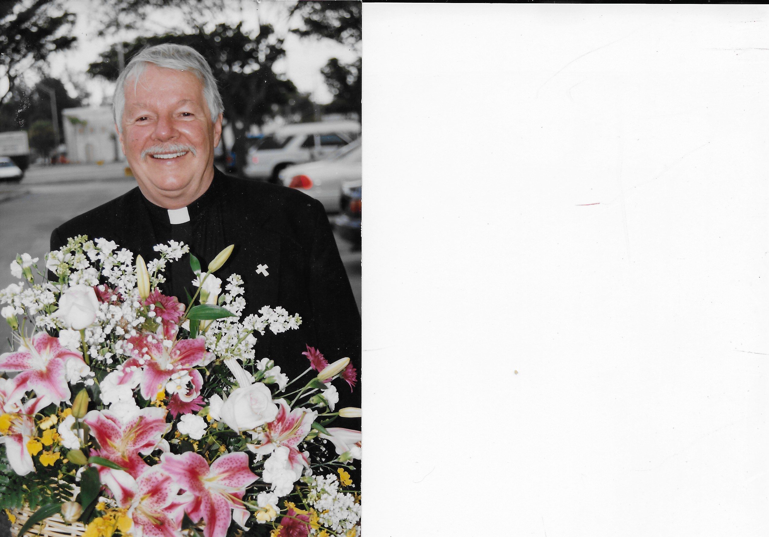 Father John Reid smiles broadly, as he holds a bountiful bouquet of beautiful flowers at the Divine Mercy Chapel in Wilton Manors FL.